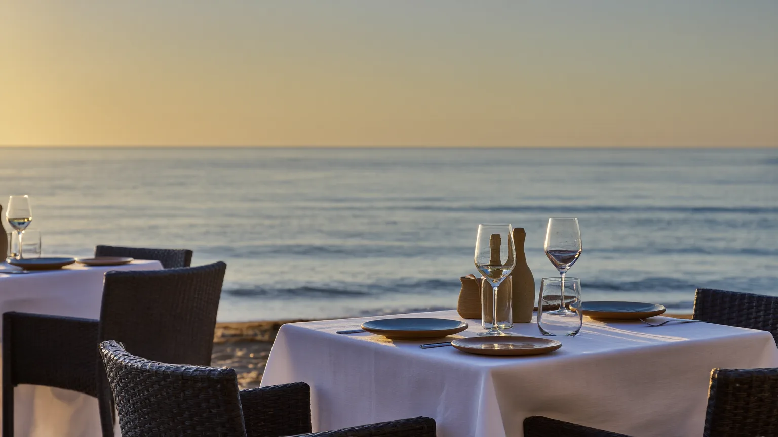 A beachfront seafood table set for dinner beside the Mediterranean at golden hour